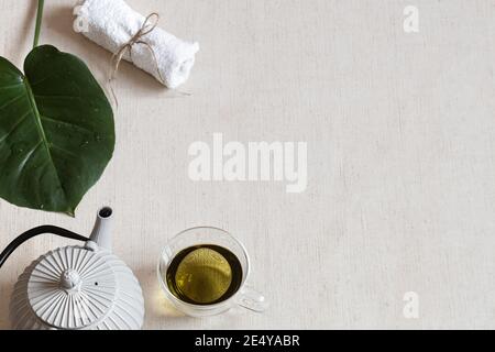 Minimalistic composition with green tea in a cup, teapot and bath accessories. Health and beauty concept. Stock Photo