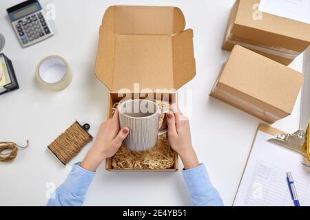 hands packing mug to parcel box at post office Stock Photo