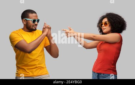 african couple in sunglasses making gun gesture Stock Photo