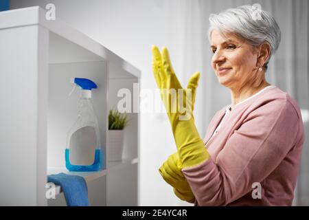 senior woman putting protective rubber gloves on Stock Photo