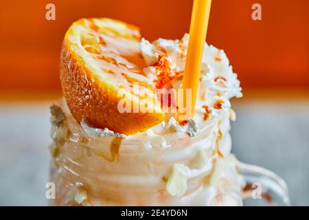 Orange smoothie with sprinkles and straw on the bright background Stock Photo