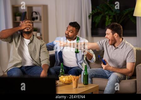 happy friends playing video games at home at night Stock Photo