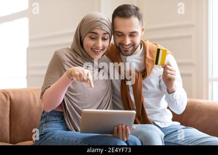 Excited Muslim Couple Shopping Online With Digital Tablet At Home Stock Photo