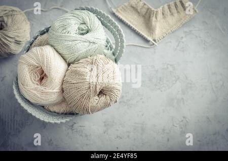 Colored yarn balls and knitting needles in basket on light background, top view Stock Photo