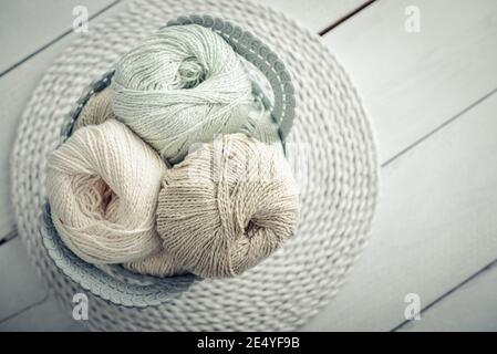 Colored yarn balls and knitting needles in basket on light background, top view Stock Photo