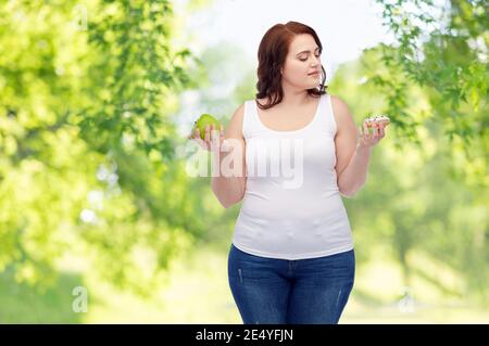 plus size woman choosing between apple and donut Stock Photo