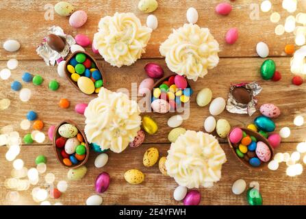 cupcakes with chocolate eggs and candies on table Stock Photo