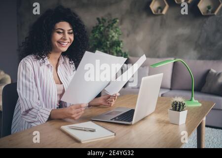 Photo portrait of smiling girl reading papers positive reports sitting in chair in industrial office indoors Stock Photo