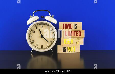 Startup and freelancer inspirational and motivational conceptual image with text inscription time is limited idea is not, wooden pegs and alarm clocks Stock Photo