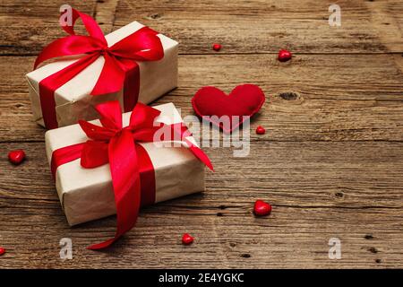 Valentine greeting card background with gift boxes, red ribbons and assorted hearts. Vintage wooden table. Wedding or Birthday concept, place for text Stock Photo