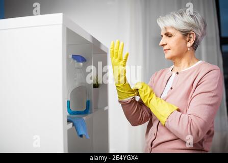senior woman putting protective rubber gloves on Stock Photo