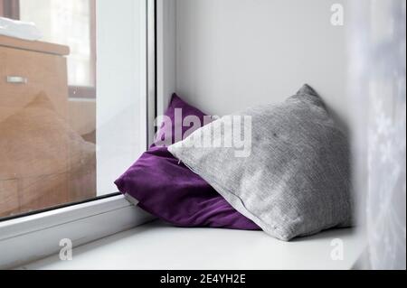 Soft cushions on white sill. Cozy pillows. Stock Photo