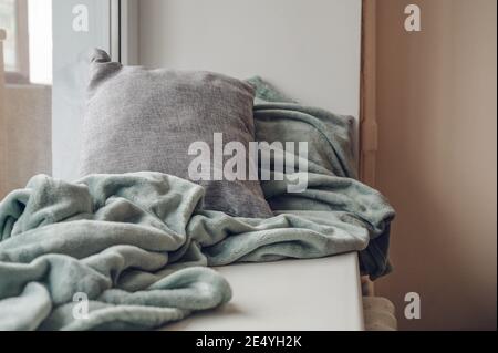 Soft cushions and fluffy plaid on white sill. Cozy pillows. Stock Photo