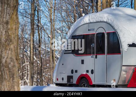 A Teardrop travel trailer on a campsite during winter season, storage, winterize Stock Photo
