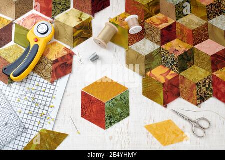 Fragment of tumbling blocks quilt, accessories for quilting on a white surface Stock Photo