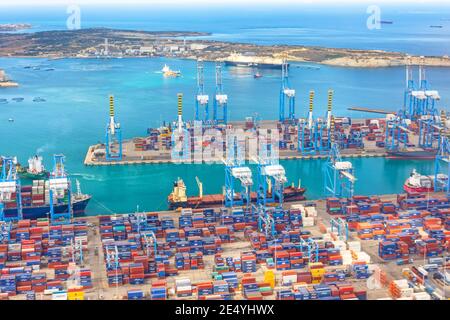 Huge ship moored to the port, cranes unload cargo. Great port, maritime transport, maritime traffic delivery concept. Malta, Il Brolli Marsaxlokk, Mal Stock Photo