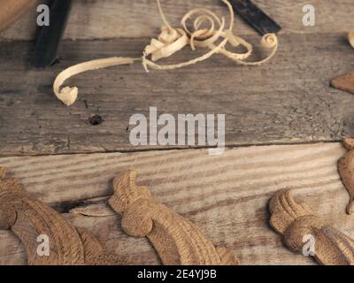 Carved oak decorative elements on a rustic workbench with chisels, text free space in the center, wood working or creativity concept Stock Photo