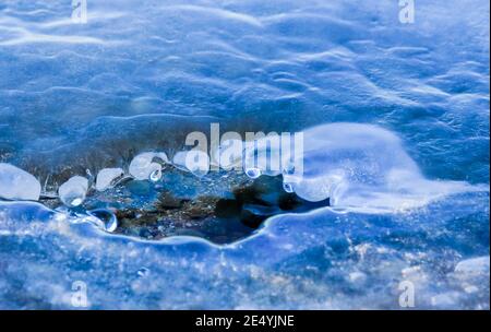 The ice formations look like beings from another planet. They have eyes and look into an ice hole in the lake. Stock Photo