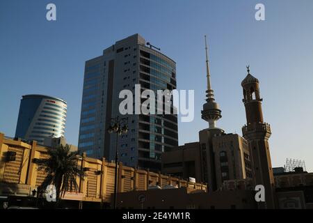 Kuwait City/Kuwait – January 10, 2021: Old mosque minaret with crescent symbol dwarfed by modern skyscrapers Stock Photo