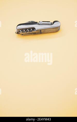 Vertical shot of a small folding pocket knife on a beige surface under the lights Stock Photo