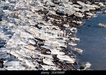 WINTER CHUNKS OR SLABS OF ICE AROUND A POTHOLE IN A ROAD Stock Photo