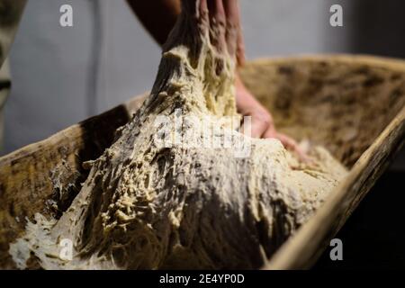 Kneading dough for the oven in a traditional wooden bread trough Stock Photo