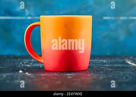 Colorful ceramic mug isolated on blue desk Stock Photo
