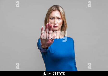 No, forbidden! Portrait of upset young woman in tight blue dress showing stop gesture, prohibition or warning expression with frowning worried face. i Stock Photo