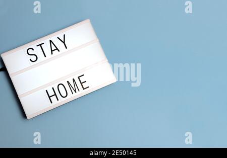'Stay at Home' message on a lightox with a blue background with copy space. Stock Photo