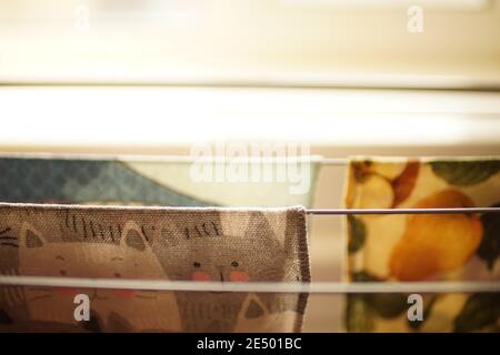 Floor-standing fold-out clothes dryer with kitchen towels on wire racks. Stock Photo