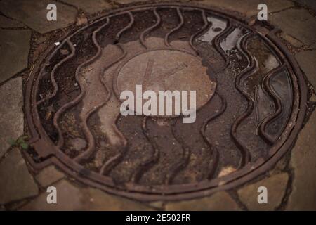 manhole with letter k wet after rain. Stock Photo