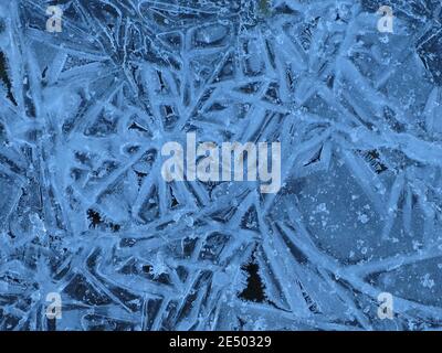 Nature's designs in winter: abstract close-up of frozen ice crystals in beautiful shapes and patterns on the surface of a watery pool. Stock Photo