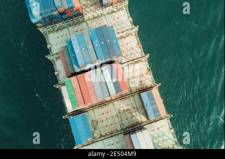 Aerial view of a containers stacked on ship below passing through the Lamma shipping channel, passing Hong Kong island enroute to the cargo terminal. The Port of Hong Kong, is a deepwater seaport dominated by trade in containerised manufactured products, and to a lesser extent raw materials and passengers. A key factor in the economic development of Hong Kong, the deep waters of Victoria Harbour provide ideal conditions for berthing and the handling of all types of vessels. It is one of the busiest ports worldwide in categories of shipping movement, cargo and passengers. © Time-Snaps Stock Photo