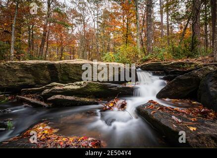 Long exposure shot of the beautiful Cheaha Falls with bright autumn color in the background. Stock Photo