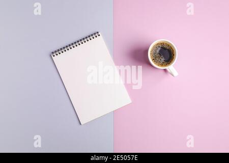 Mockup on a gray-pink background from a blank sheet of paper in a notebook and a cup of coffee. Selective focus, top view. Stock Photo