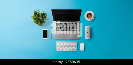 Flat lay top view office desk working space with laptop on blue background. Copy space. Stock Photo
