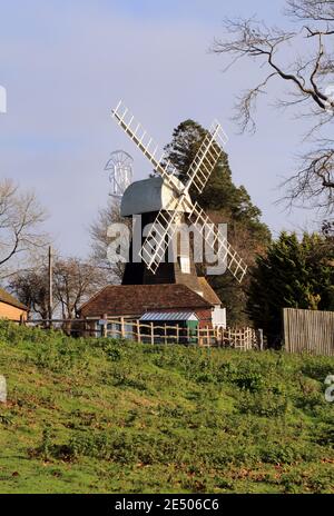 Charing Windmill, Charing, Kent, England. Early 19th century smock mill faced with weatherboarding. Octagonal red brick 'round-house' with wooden plat Stock Photo