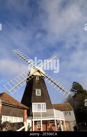 Charing Windmill, Charing, Kent, England. Early 19th century smock mill faced with weatherboarding. Octagonal red brick 'round-house' with wooden plat Stock Photo