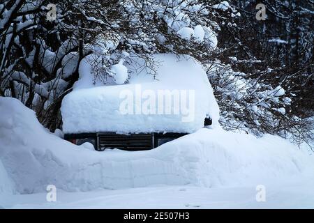 The entire passenger car is covered (except for the radiator grille) with snow in a heavy snowstorm. Northern winter Stock Photo