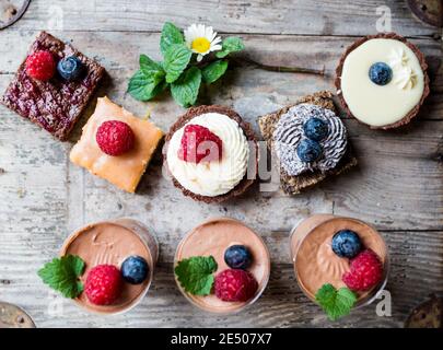 Selection of colorful and delicious cake desserts on wooden table. Stock Photo