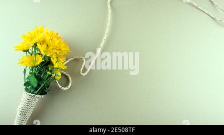 Flat lay of a bouquet of yellow mums or Chrysanthemum flowers, binding with gray white rope on grey background. Stock Photo