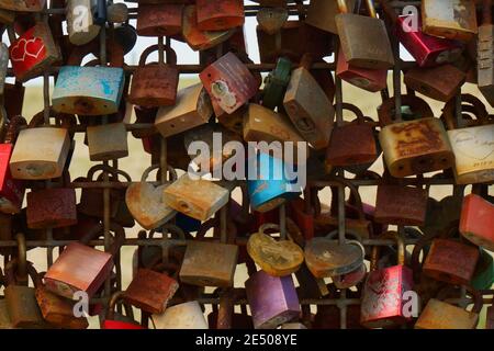 Rusted love locks on a fence.  The rusted love locks look old, but the sea breeze likely has sped up the process. Padlocks. Stock Photo