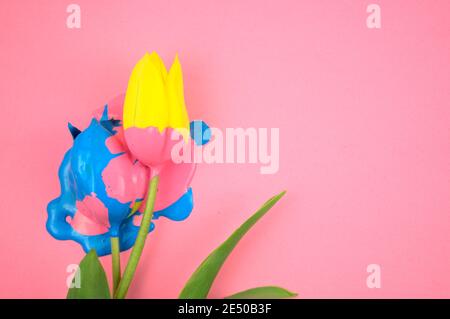 Colorful acrylic and yellow flower, tulip flat lay on clear pink background. Dripping vivid candy ink medium colors, blue, pink on floral. Stock Photo