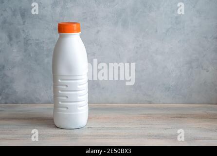 A white milk bottle with an orange lid on a gray background. Stock Photo