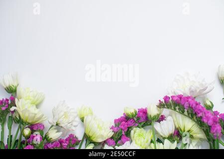 Pink statice and white chrysanthemum flowers on a white background. Top view. Copy space. Space for the text. The concept of the holiday. Stock Photo