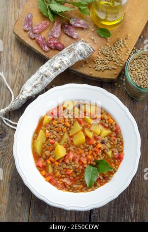 Lentil soup with chorizo on a rustic table. Top view Stock Photo