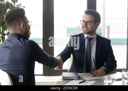 Smiling hr manager shaking hand of successful candidate after interview Stock Photo