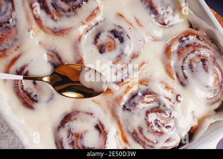 Spoon lying on delicious homemade freshly baked cinnamon rolls Stock Photo