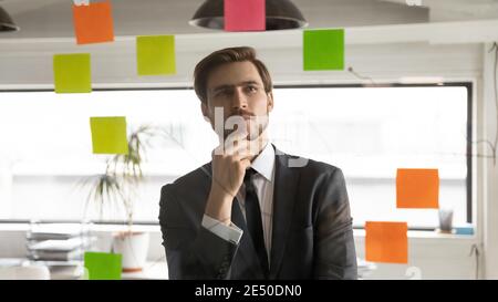 Close up thoughtful businessman reading notes on stickers, pondering strategy Stock Photo