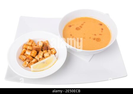 Cream soup with breadcrumbs on a white ceramic tray. All this isolated in a white background. Close-up. Stock Photo